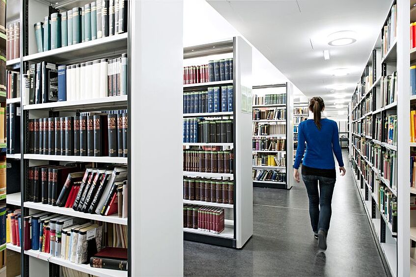 Studentin steht in der Bibliothek.